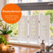 Wit houten raamscherm met decoratieve bladuitsnedes op een vensterbank in een sfeervol interieur – Raamschermen van Canvasscherm.nl.