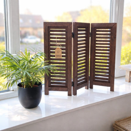 Houten decoratief raamscherm met 3 panelen op een vensterbank, met plant en natuurlijk daglicht