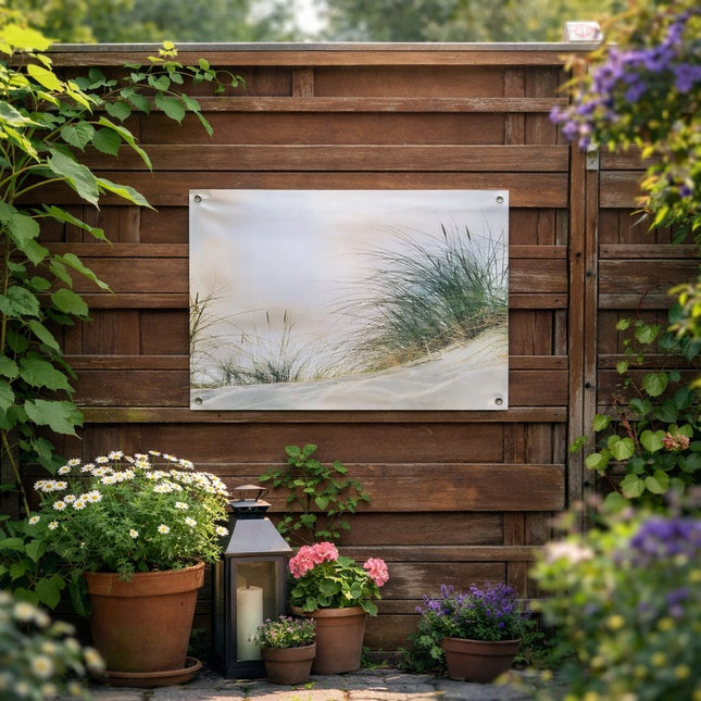 Tuinposter met duinlandschap bevestigd aan houten schutting in groene tuin.