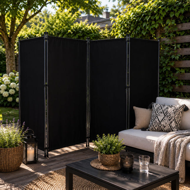 Modern zwart kamerscherm voor buitengebruik, geplaatst naast een loungeset op een zonnig terras. Het scherm biedt extra privacy, beschutting en bescherming tegen de zon in de tuin.